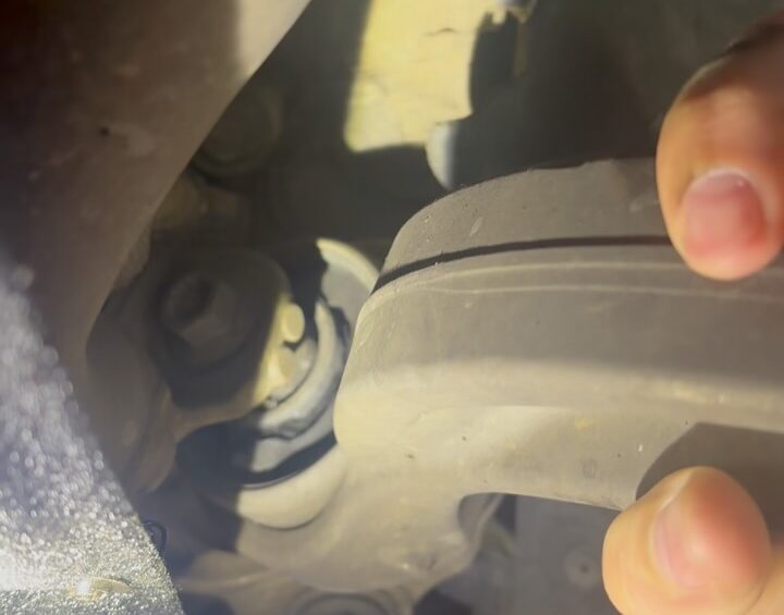 Audi Q7 lower control arm with a torn bush, moved by hand to show the play
