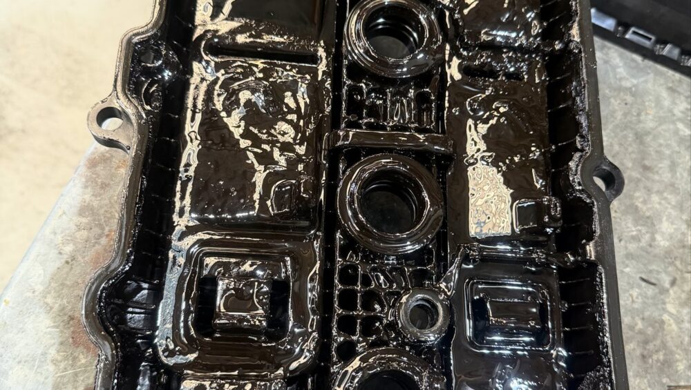 Underside of a Hyundai i30 rocker cover caked in black engine oil sludge