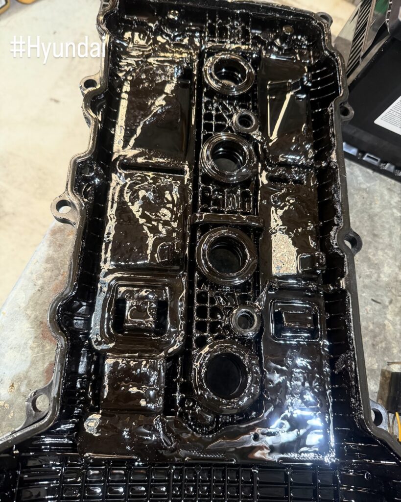 Underside of a Hyundai i30 rocker cover caked in black engine oil sludge
