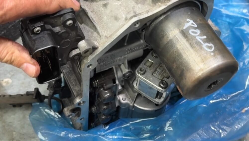 Used VW DSG mechatronic unit marked Polo on the workbench after removal